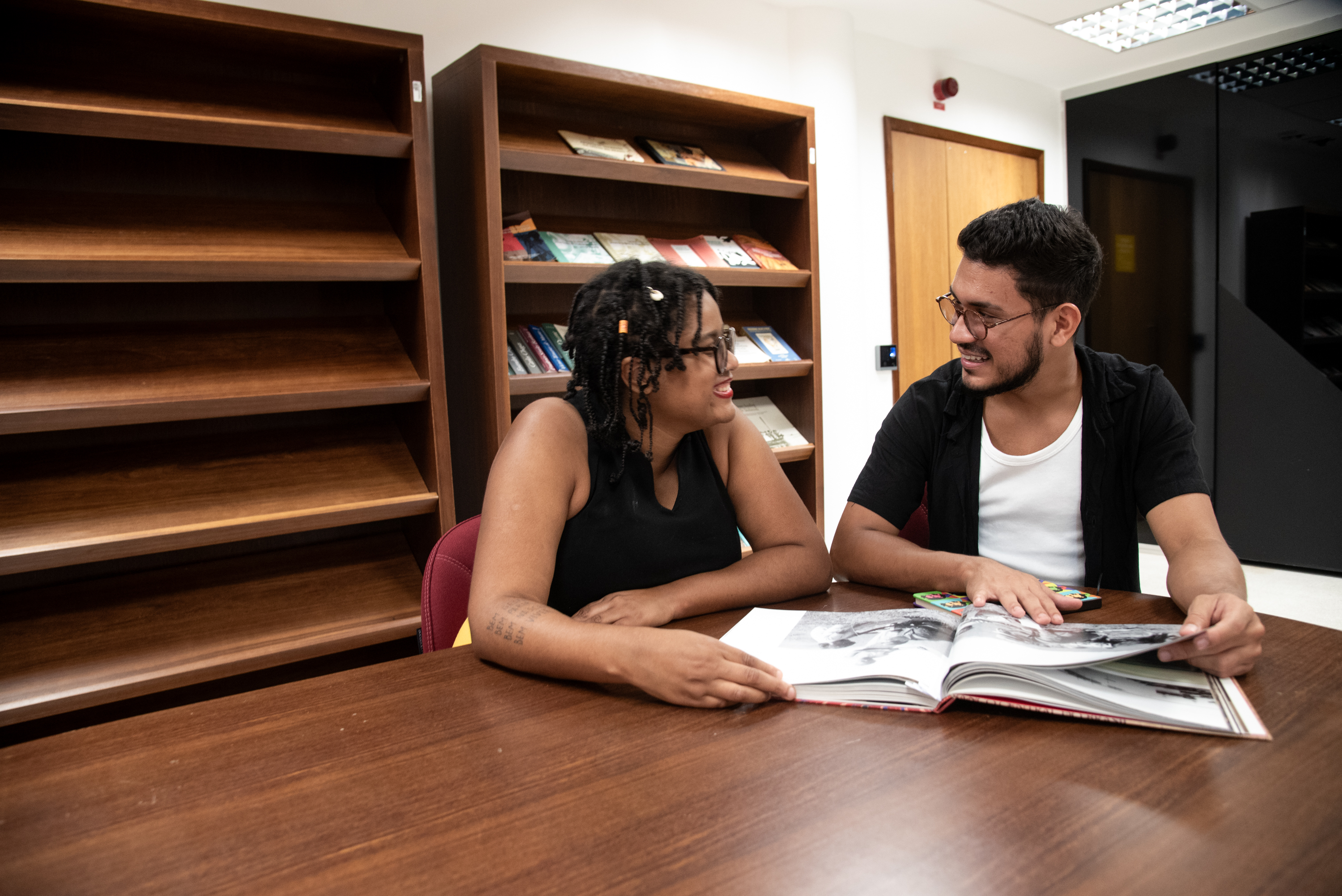 Um homem e uma mulher em uma mesa lendo um livro