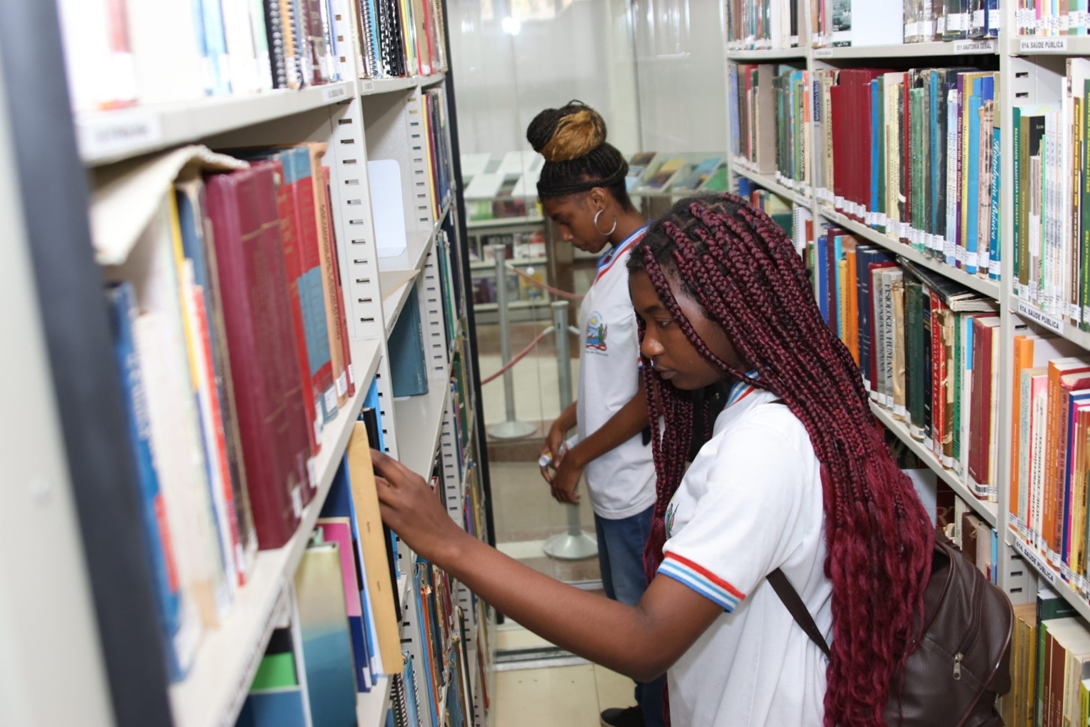 Duas pessoas procurando livros na biblioteca